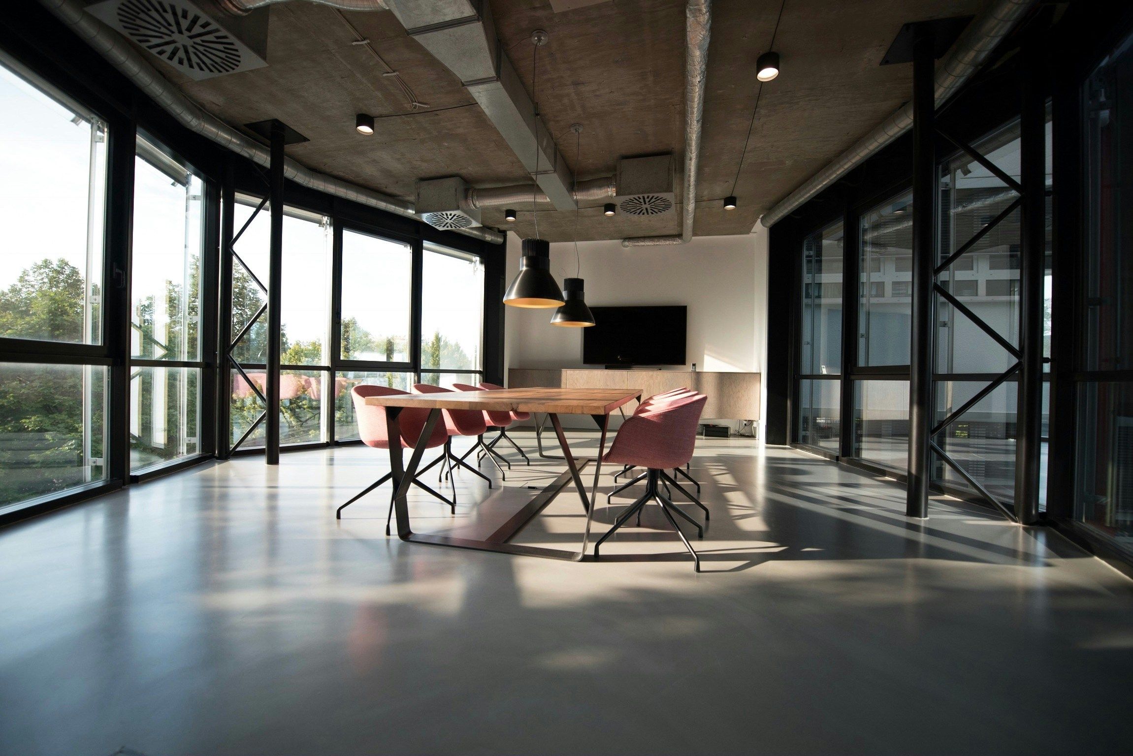 An empty boardroom with a meeting table and floor-to-ceiling windows