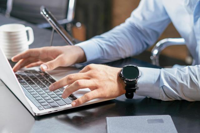 Hands typing on a laptop at a desk